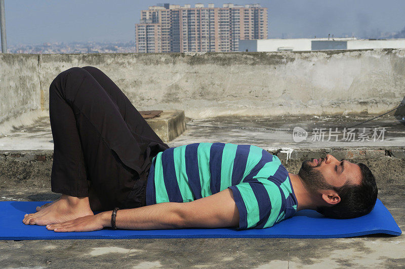 印度男子在屋顶上练习桥瑜伽(Setu Bandha Sarvangasana)，印度德里